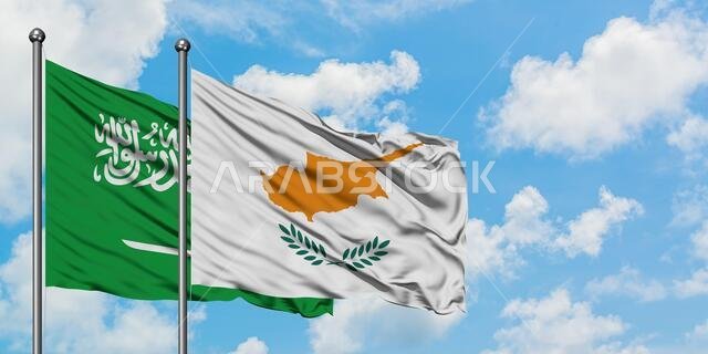 يرفرف علم المملكة العربية السعودية وعلم قبرص معاً في مهب الريح أمام سماء زرقاء صافية تتلألأ بالغيوم البيضاء. مفهوم الدبلوماسية، العلاقات الدولية.