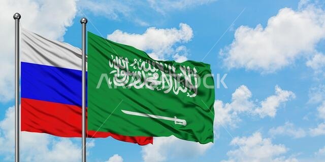 يرفرف علم روسيا والسعودية معاً في مهب الريح أمام سماء زرقاء صافية تتلألأ فيها الغيوم البيضاء. مفهوم الدبلوماسية، العلاقات الدولية.