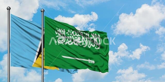 يرفرف علم سانت لوسيا وعلم المملكة العربية السعودية معاً في مهب الريح أمام سماء زرقاء ملبدة بالغيوم البيضاء. مفهوم الدبلوماسية، العلاقات الدولية.