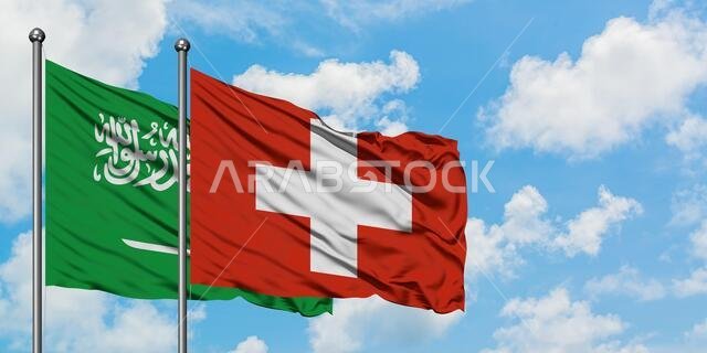 Saudi Arabia and Switzerland flag waving in the wind against white cloudy blue sky together. Diplomacy concept, international relations.