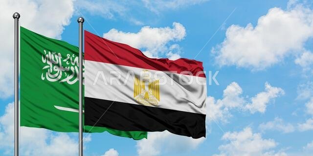 يرفرف علم المملكة العربية السعودية وعلم مصر معاً في مهب الريح أمام سماء زرقاء صافية تتلألأ فيها الغيوم البيضاء. مفهوم الدبلوماسية، العلاقات الدولية.