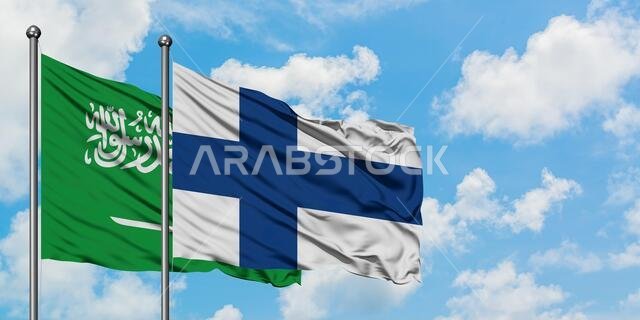 يرفرف علم المملكة العربية السعودية وفنلندا معاً في مهب الريح أمام سماء زرقاء صافية تتلألأ فيها الغيوم البيضاء. مفهوم الدبلوماسية، العلاقات الدولية.