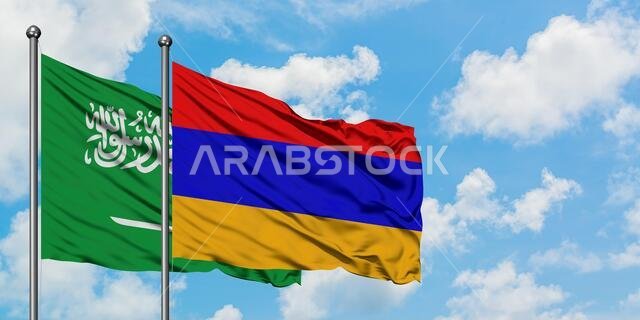 Saudi Arabia and Armenia flag waving in the wind against white cloudy blue sky together. Diplomacy concept, international relations.