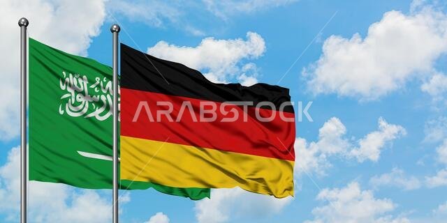 Saudi Arabia and Germany flag waving in the wind against white cloudy blue sky together. Diplomacy concept, international relations.