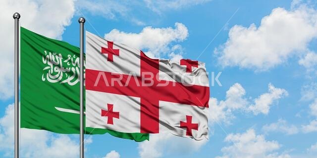 يرفرف علم المملكة العربية السعودية وعلم جورجيا معاً في مهب الريح أمام سماء زرقاء صافية تتلألأ فيها الغيوم البيضاء. مفهوم الدبلوماسية، العلاقات الدولية.