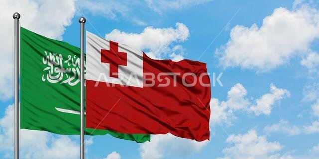 يرفرف علم المملكة العربية السعودية وعلم تونغا معاً في مهب الريح أمام سماء زرقاء صافية تتخللها غيوم بيضاء. مفهوم الدبلوماسية، العلاقات الدولية.