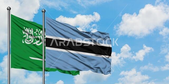 يرفرف علم المملكة العربية السعودية وعلم بوتسوانا معاً في مهب الريح أمام سماء زرقاء صافية تتلألأ فيها الغيوم البيضاء. مفهوم الدبلوماسية، العلاقات الدولية.