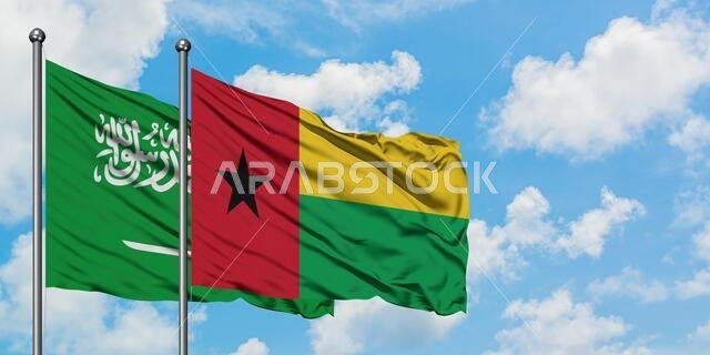 Saudi Arabia and Guinea Bissau flag waving in the wind against white cloudy blue sky together. Diplomacy concept, international relations.