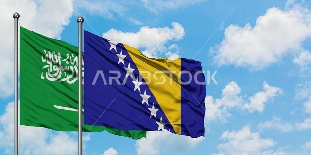 Saudi Arabia and Bosnia Herzegovina flag waving in the wind against white cloudy blue sky together. Diplomacy concept, international relations.