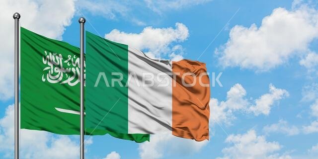 Saudi Arabia and Ireland flag waving in the wind against white cloudy blue sky together. Diplomacy concept, international relations.