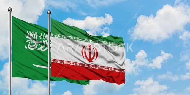 يرفرف علم السعودية وإيران معاً في مهب الريح أمام سماء زرقاء صافية تتلألأ بالغيوم البيضاء. مفهوم الدبلوماسية، العلاقات الدولية.