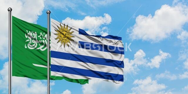 يرفرف علم المملكة العربية السعودية وعلم أوروغواي معاً في مهب الريح أمام سماء زرقاء صافية تتخللها غيوم بيضاء. مفهوم الدبلوماسية، العلاقات الدولية. يرفرف علم المملكة العربية السعودية وعلم أوروغواي معاً في مهب الريح أمام سماء زرقاء صافية تتخللها غيوم بيضاء. مفهوم الدبلوماسية، العلاقات الدولية.