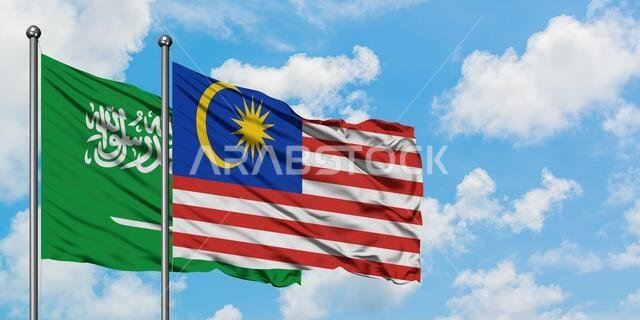Saudi Arabia and Malaysia flag waving in the wind against white cloudy blue sky together. Diplomacy concept, international relations.