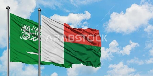 يرفرف علم المملكة العربية السعودية وعلم مدغشقر معاً في مهب الريح أمام سماء زرقاء صافية تتخللها غيوم بيضاء. مفهوم الدبلوماسية، العلاقات الدولية.