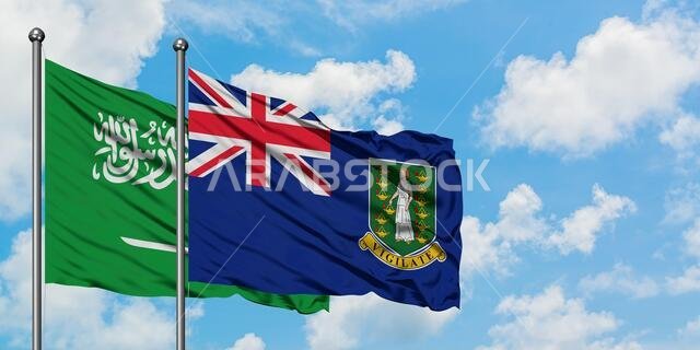 يرفرف علم المملكة العربية السعودية وجزر العذراء البريطانية معاً في مهب الريح أمام سماء زرقاء صافية تتلألأ بالغيوم البيضاء. مفهوم الدبلوماسية، العلاقات الدولية.