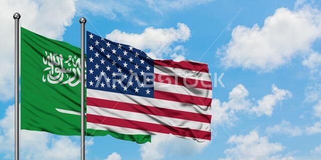 Saudi Arabia and United States flag waving in the wind against white cloudy blue sky together. Diplomacy concept, international relations.