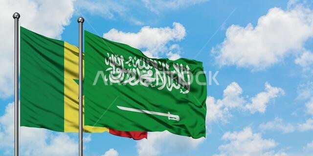 يرفرف علم السنغال والسعودية معاً في مهب الريح أمام سماء زرقاء صافية تتلألأ بالغيوم البيضاء. مفهوم الدبلوماسية، العلاقات الدولية.
