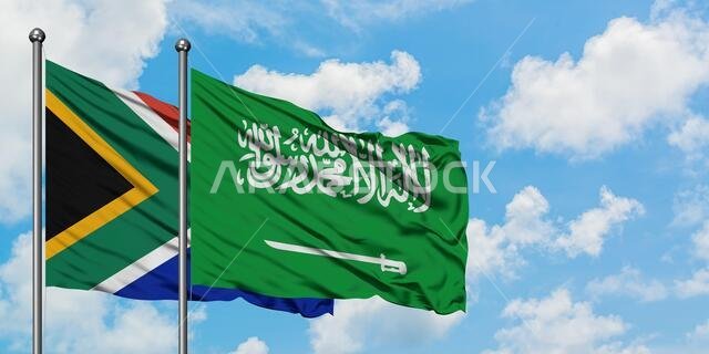 يرفرف علم جنوب أفريقيا وعلم المملكة العربية السعودية معاً في مهب الريح أمام سماء زرقاء صافية تتخللها غيوم بيضاء. مفهوم الدبلوماسية، العلاقات الدولية.
