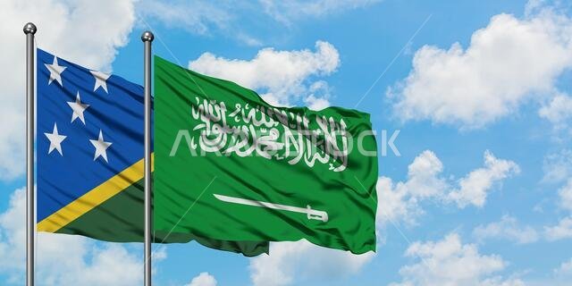 يرفرف علم جزر سليمان وعلم المملكة العربية السعودية معاً في مهب الريح أمام سماء زرقاء صافية تتخللها غيوم بيضاء. مفهوم الدبلوماسية، العلاقات الدولية.