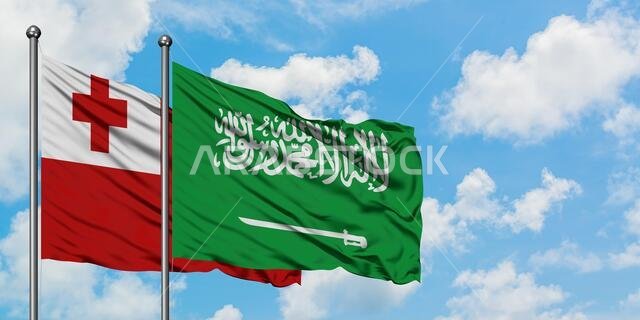 يرفرف علم تونغا وعلم المملكة العربية السعودية معاً في مهب الريح أمام سماء زرقاء صافية تتخللها غيوم بيضاء. مفهوم الدبلوماسية، العلاقات الدولية.