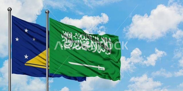يرفرف علم توكيلاو وعلم المملكة العربية السعودية معاً في مهب الريح أمام سماء زرقاء ملبدة بالغيوم البيضاء. مفهوم الدبلوماسية، العلاقات الدولية.