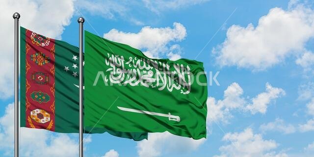 يرفرف علم تركمانستان والسعودية معاً في مهب الريح أمام سماء زرقاء صافية تتلألأ فيها الغيوم البيضاء. مفهوم الدبلوماسية، العلاقات الدولية.