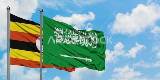 يرفرف علم أوغندا وعلم المملكة العربية السعودية معاً في مهب الريح أمام سماء زرقاء صافية تتخللها غيوم بيضاء. مفهوم الدبلوماسية، العلاقات الدولية.