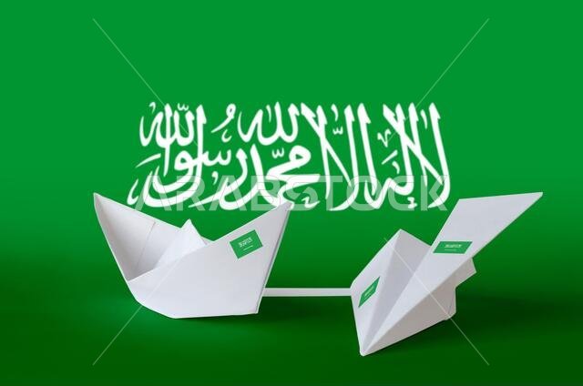 علم المملكة العربية السعودية مُصوَّر على طائرة وقارب من الورق المقوى بتقنية الأوريغامي. مفهوم الفنون اليدوية الشرقية.