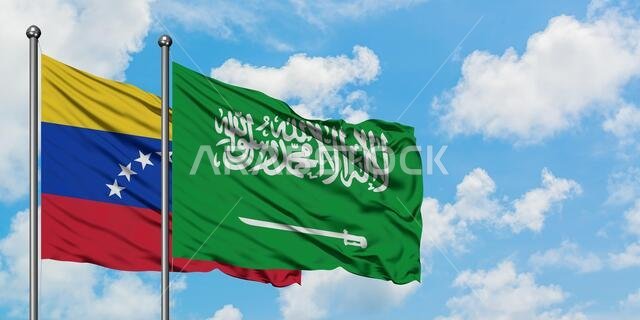 يرفرف علم فنزويلا وعلم السعودية معاً في مهب الريح أمام سماء زرقاء ملبدة بالغيوم البيضاء. مفهوم الدبلوماسية، العلاقات الدولية.