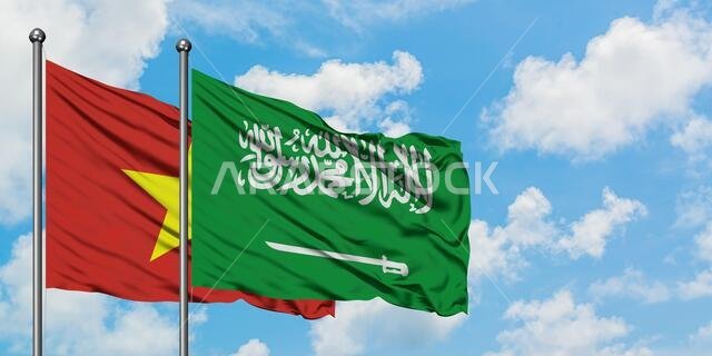 يرفرف علم فيتنام وعلم السعودية معاً في مهب الريح أمام سماء زرقاء صافية تتلألأ بالغيوم البيضاء. مفهوم الدبلوماسية، العلاقات الدولية.