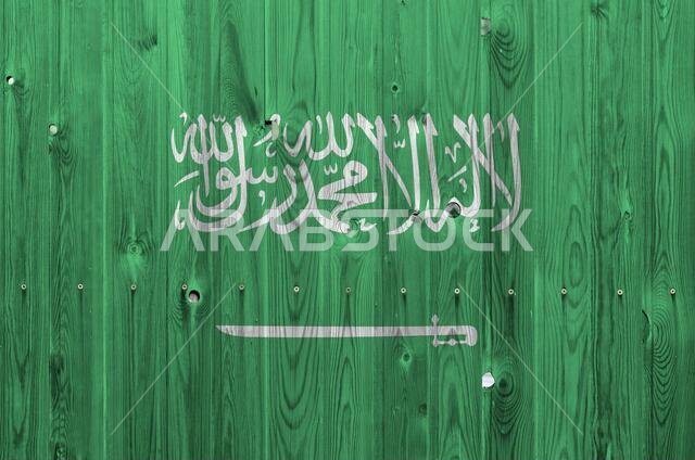 Saudi Arabia flag depicted in bright paint colors on old wooden wall close up. Textured banner on rough background