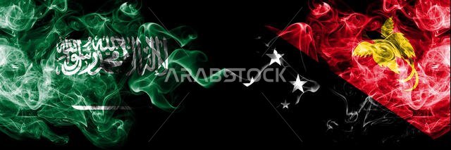أعلام المملكة العربية السعودية وبابوا غينيا الجديدة الدخانية الغامضة موضوعة جنبًا إلى جنب. أعلام دخانية حريرية ملونة سميكة من اللغة العربية والعربية وبابوا غينيا الجديدة