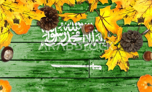 Saudi Arabia flag on autumn wooden background with leaves and good place for your text