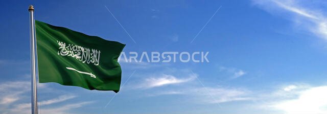 يرفرف علم المملكة العربية السعودية مع الريح والسماء في الخلفية