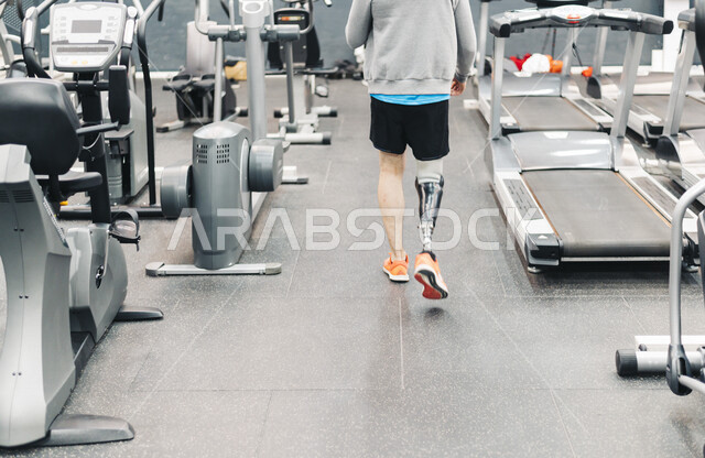 شاب من ذوي الهمم في النادي الرياضي , يقوم بالاستعداد لعمل رياضة , اطراف صناعية , لياقة جسدية , حياة صحية .