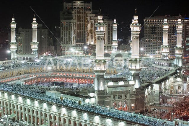 يتجمع آلاف المسلمين حول الكعبة المشرفة، المكعب الموجود في وسط المسجد الحرام، أثناء صلاة العشاء في مدينة مكة المكرمة بالمملكة العربية السعودية.