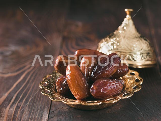 Metal plate of dates on dark wooden table. Dried dates with copy space.
