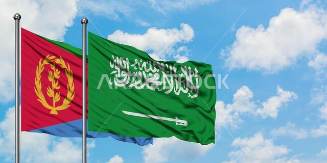 يرفرف علما إريتريا والسعودية معاً في مهب الريح أمام سماء زرقاء صافية تتلألأ فيها الغيوم البيضاء. مفهوم الدبلوماسية، العلاقات الدولية.