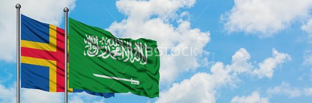 ترفرف أعلام جزر آلاند والمملكة العربية السعودية معاً في مهب الريح أمام سماء زرقاء ملبدة بالغيوم البيضاء. مفهوم الدبلوماسية، العلاقات الدولية.