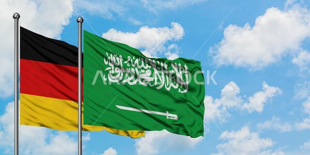 يرفرف علم ألمانيا والسعودية معاً في مهب الريح أمام سماء زرقاء صافية تتلألأ بالغيوم البيضاء. مفهوم الدبلوماسية، العلاقات الدولية.