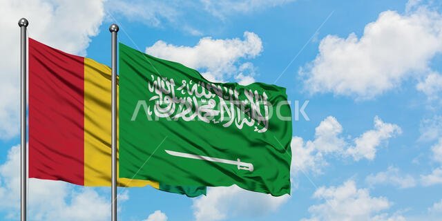 يرفرف علم غينيا وعلم السعودية معاً في مهب الريح أمام سماء زرقاء ملبدة بالغيوم البيضاء. مفهوم الدبلوماسية، العلاقات الدولية.