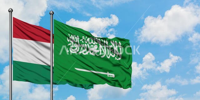 Hungary and Saudi Arabia flag waving in the wind against white cloudy blue sky together. Diplomacy concept, international relations.