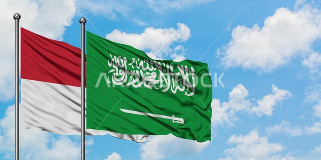 يرفرف علم العراق والسعودية معاً في مهب الريح أمام سماء زرقاء صافية تتلألأ بالغيوم البيضاء. مفهوم الدبلوماسية، العلاقات الدولية.