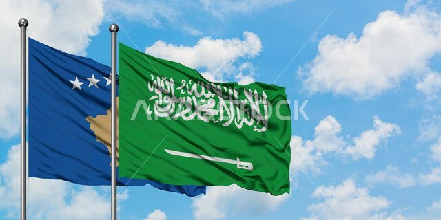يرفرف علم كوسوفو وعلم السعودية معاً في مهب الريح أمام سماء زرقاء ملبدة بالغيوم البيضاء. مفهوم الدبلوماسية، العلاقات الدولية.