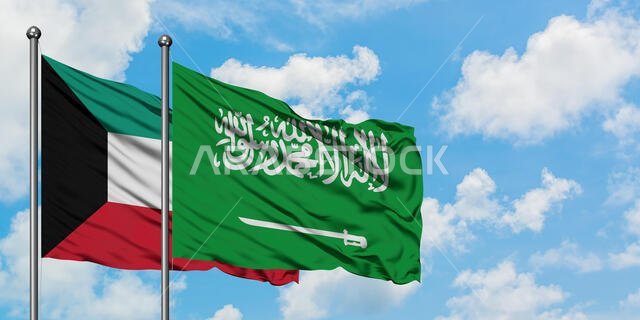 يرفرف علم الكويت والسعودية معاً في مهب الريح أمام سماء زرقاء صافية تتلألأ بالغيوم البيضاء. مفهوم الدبلوماسية، العلاقات الدولية.