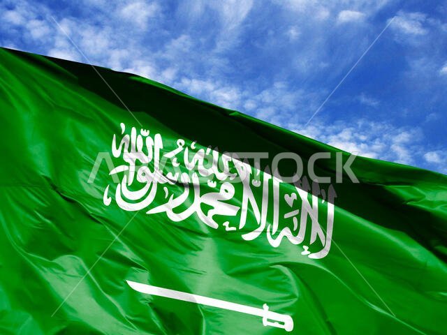 علم المملكة العربية السعودية يرفرف عن قرب أمام السماء الزرقاء