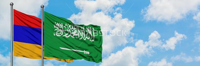 يرفرف علم أرمينيا والسعودية معاً في مهب الريح أمام سماء زرقاء صافية تتلألأ بالغيوم البيضاء. مفهوم الدبلوماسية، العلاقات الدولية.