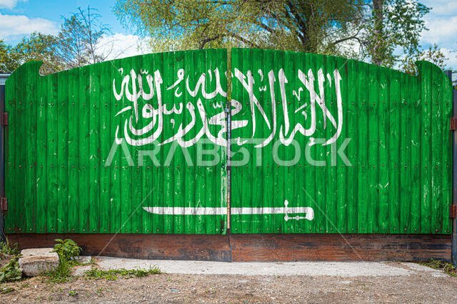 صورة مقرّبة للعلم الوطني للمملكة العربية السعودية على بوابة خشبية عند مدخل المنطقة المغلقة في يوم صيفي. مفهوم تخزين البضائع