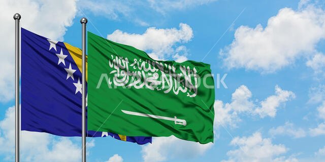 يرفرف علم البوسنة والهرسك وعلم المملكة العربية السعودية معاً في مهب الريح أمام سماء زرقاء صافية تتلألأ بالغيوم البيضاء. مفهوم الدبلوماسية، العلاقات الدولية.