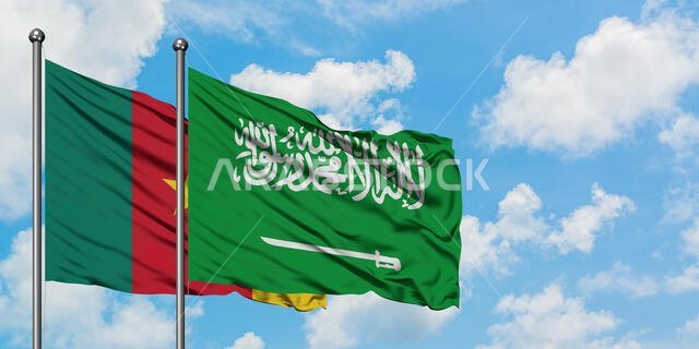 يرفرف علم الكاميرون وعلم المملكة العربية السعودية معاً في مهب الريح أمام سماء زرقاء صافية تتخللها غيوم بيضاء. مفهوم الدبلوماسية، العلاقات الدولية.